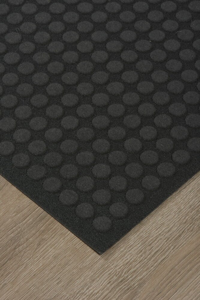 Tumma ovimatto ympyräkuviolla puulattialla.