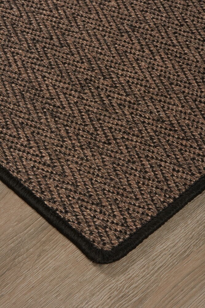 Ruskea ovimatto mustalla siksak-kuviolla lattialla.