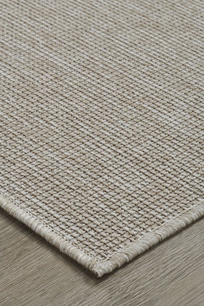 Beige ovimatto, jossa on kudottu rakenne puulattialla.