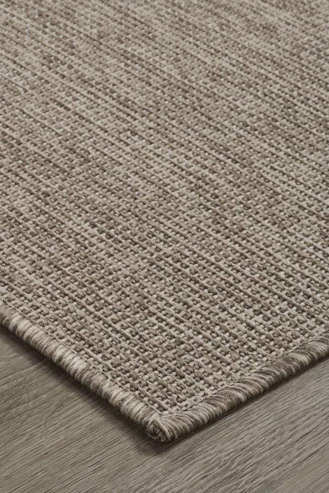 Ruskea ovenmatto, jossa on kudottu rakenne puulattialla.