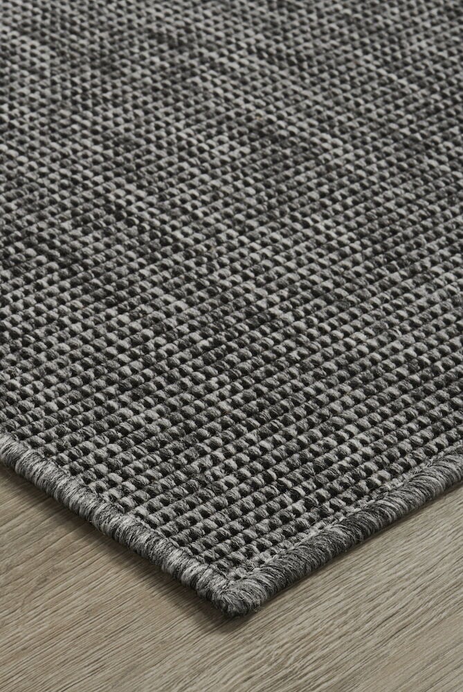Harmaa ovimatto, jossa on kudottu kuvio lattialla.