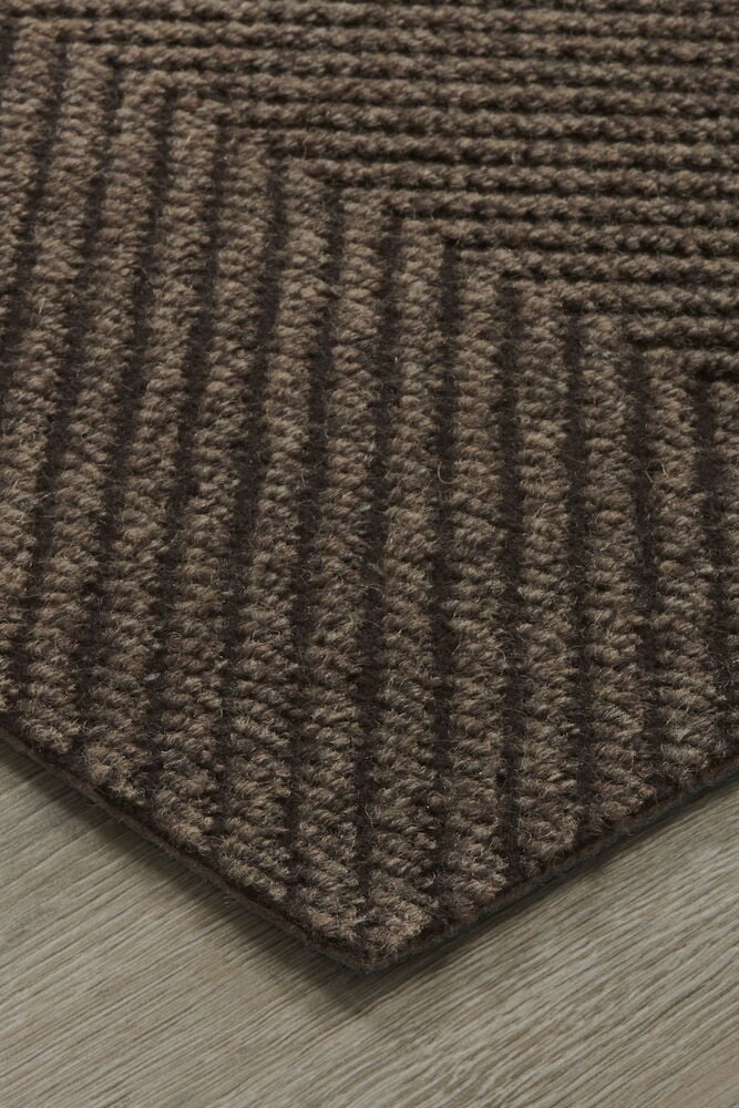 Brun dörrmatta med ränder på trägolv.