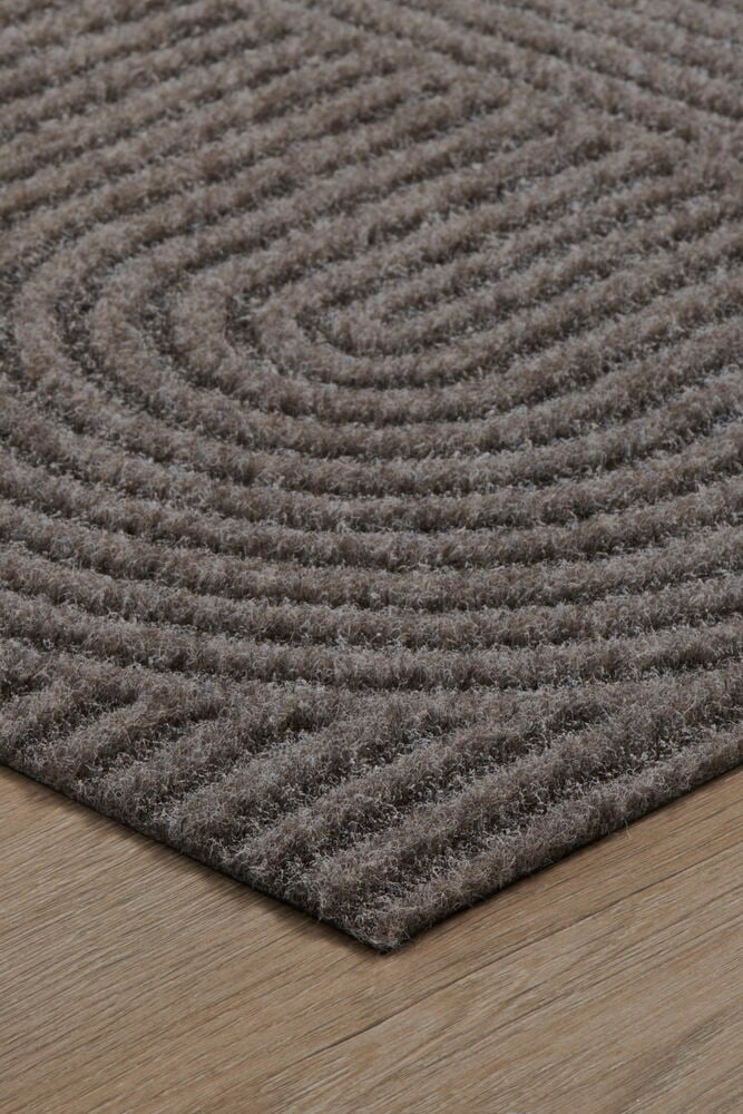 Harmaa ovimatto kaari-kuviolla puulattialla.