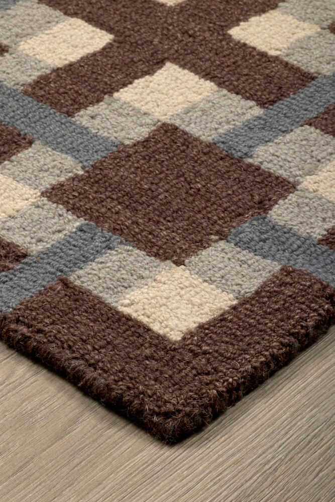 Et brunt, beige, lyseblått og grått rutete ullteppe med diamantmønster.