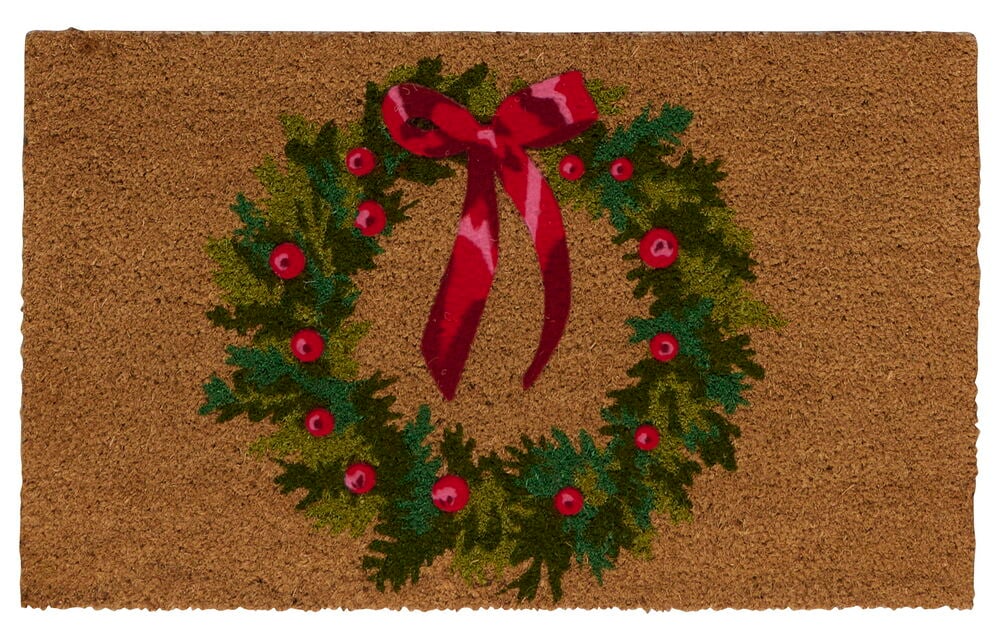 Eine braune Natur Kokosfaser Fußmatte mit grünem Weihnachtskranzdesign, roten Beeren und einer roten Schleife.