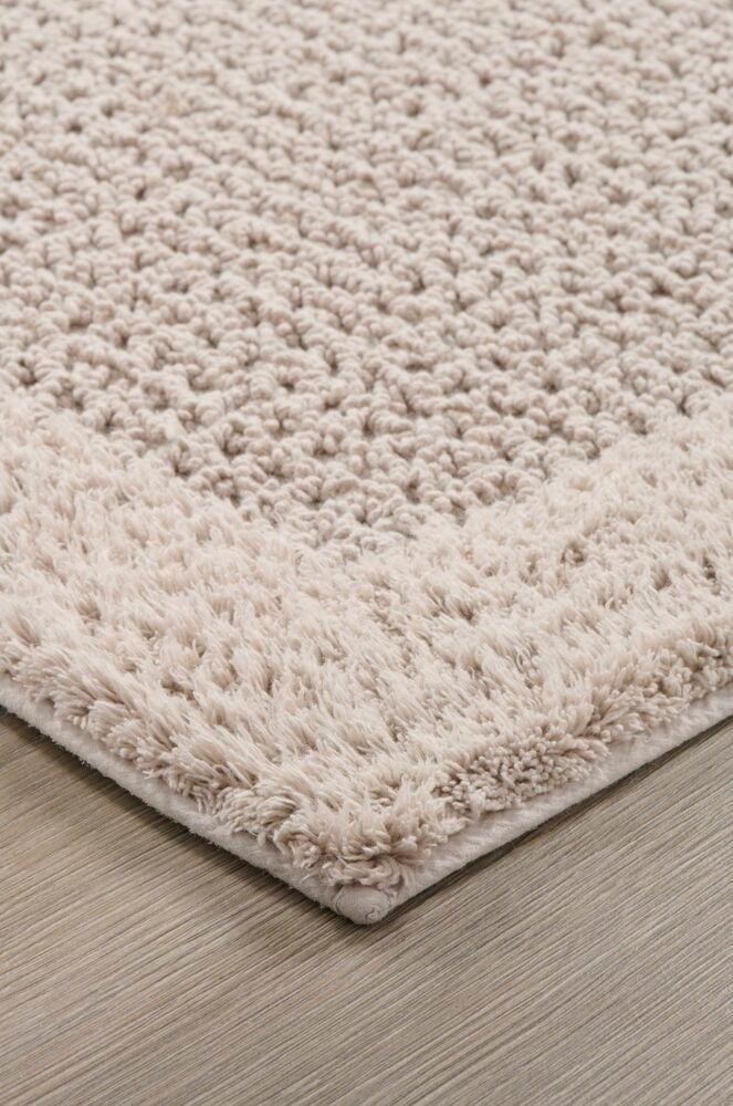 Beige suorakulmainen kylpyhuonematto, jossa on strukturoitu pinta.