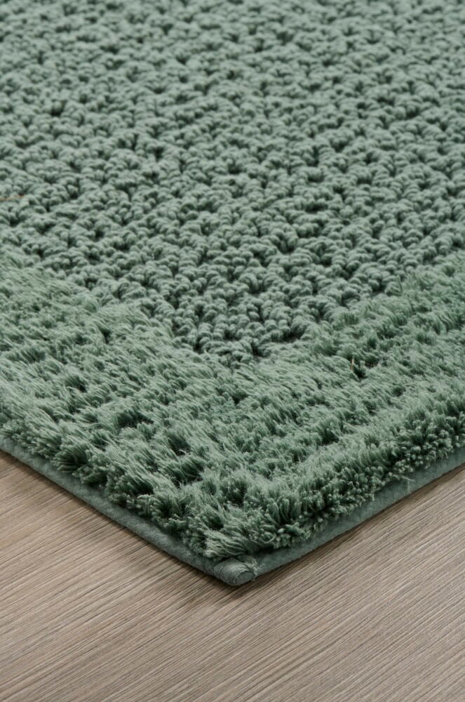 Grön badrumsmatta med struktur på trägolv.