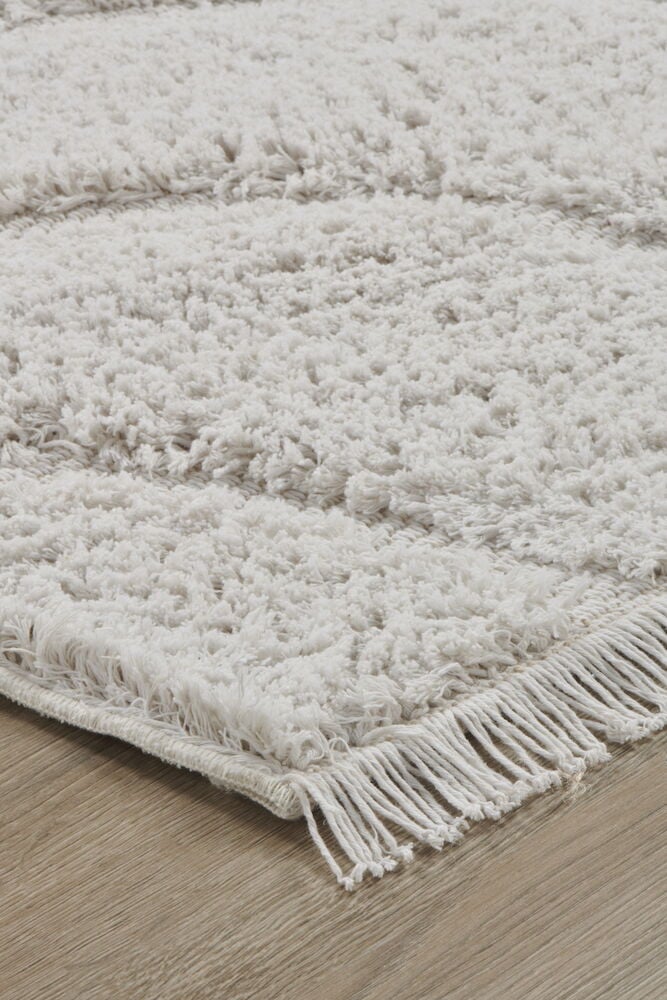 Vit matta med fransar på träfärgat golv.