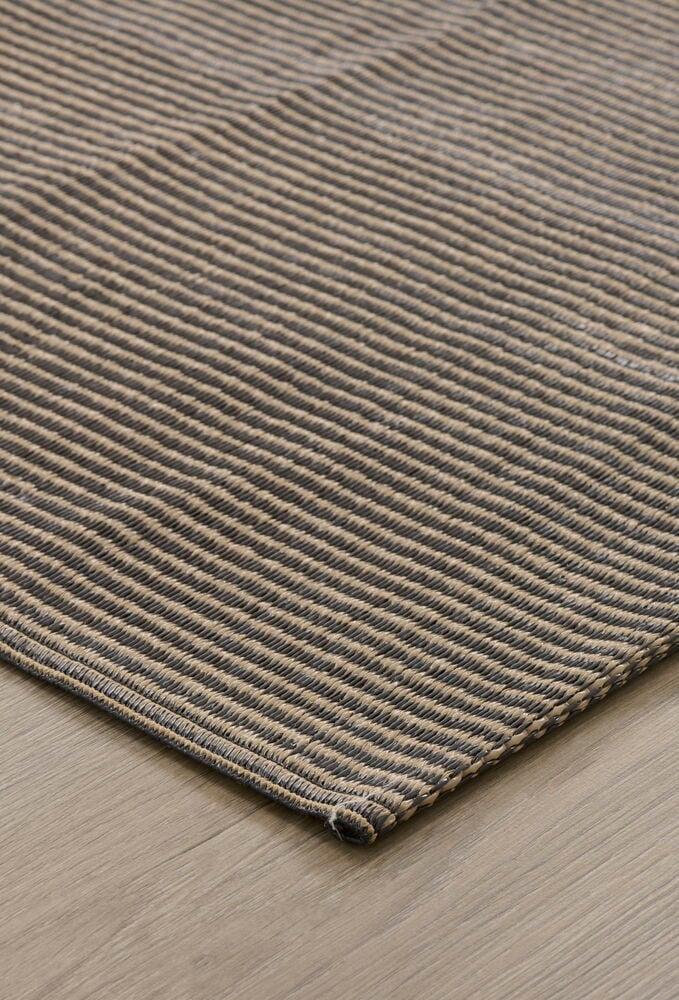Brun polypropenmatta med randigt mönster på trägolv.