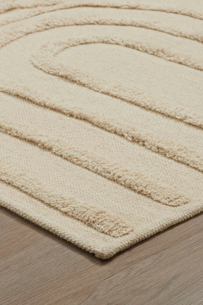 Beige gångmatta i bomull med tuftat böljande mönster.