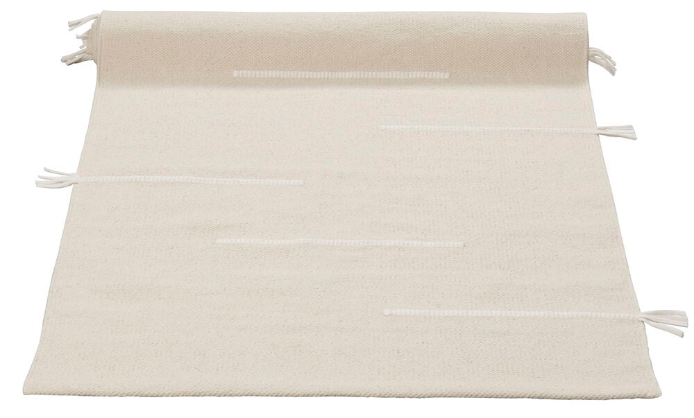 Käsinkudottu puuvillamatto luonnonvärissä, jossa on hillitty kuvio.