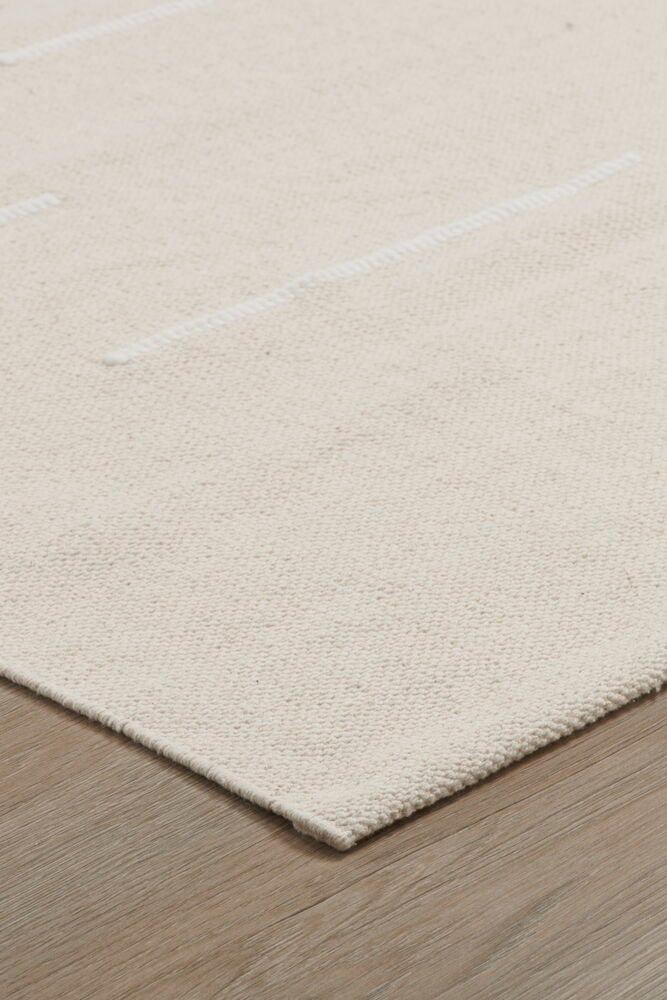 Handvävd naturfärgad bomullsmatta på trägolv.