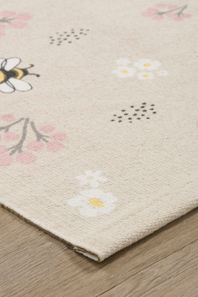 Beigefärgad matta med humla och blommotiv på golv.