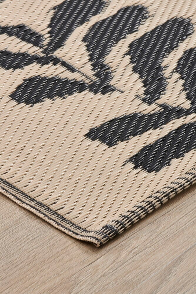 Beige bastmatta med svart bladmotiv på golv.