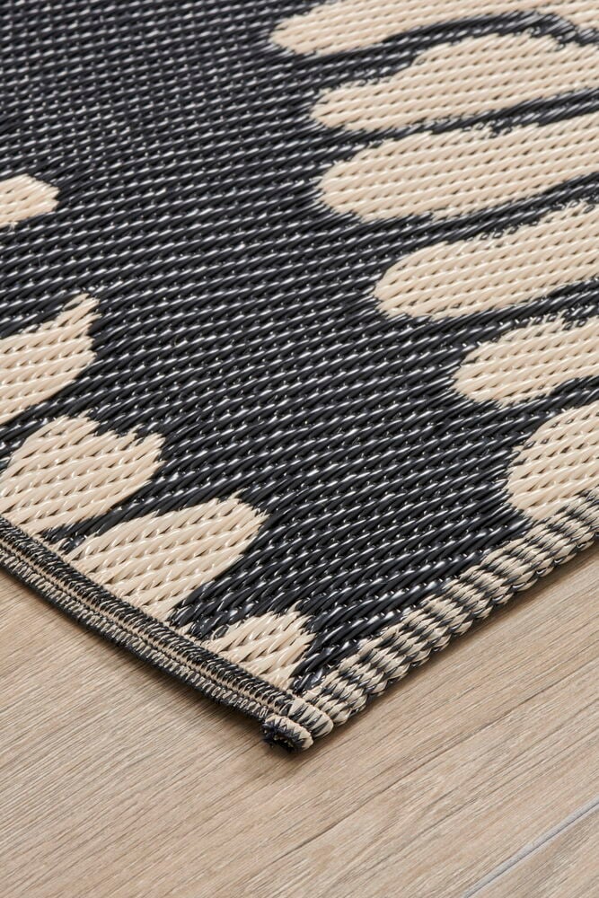 Beige bastmatta med lövmönster på trägolv.