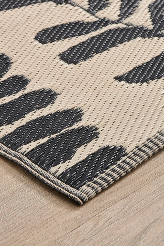 Beige bastmatta med bladmotiv på trägolv.