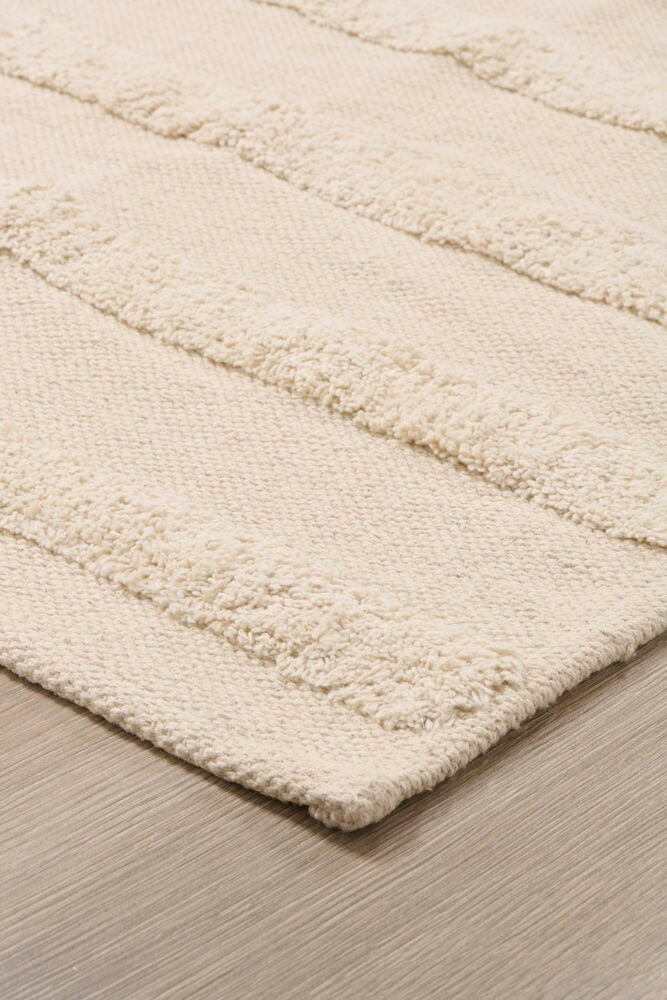 Randig beige bomullsmatta på trägolv.