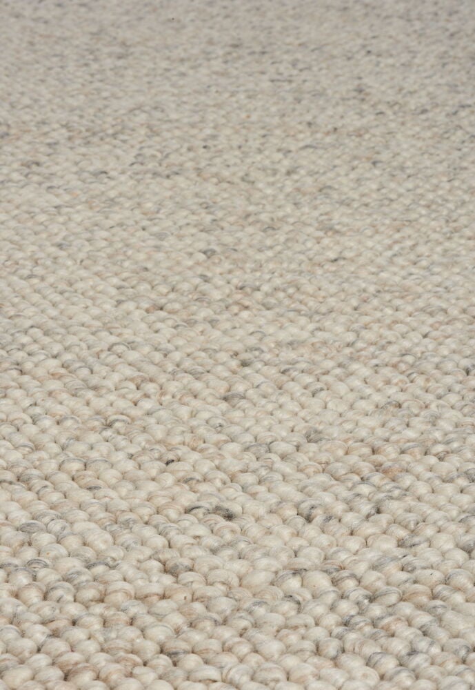 Käsinkudottu luonnonvärinen villamatto, jossa pieniä huovutettuja palloja.