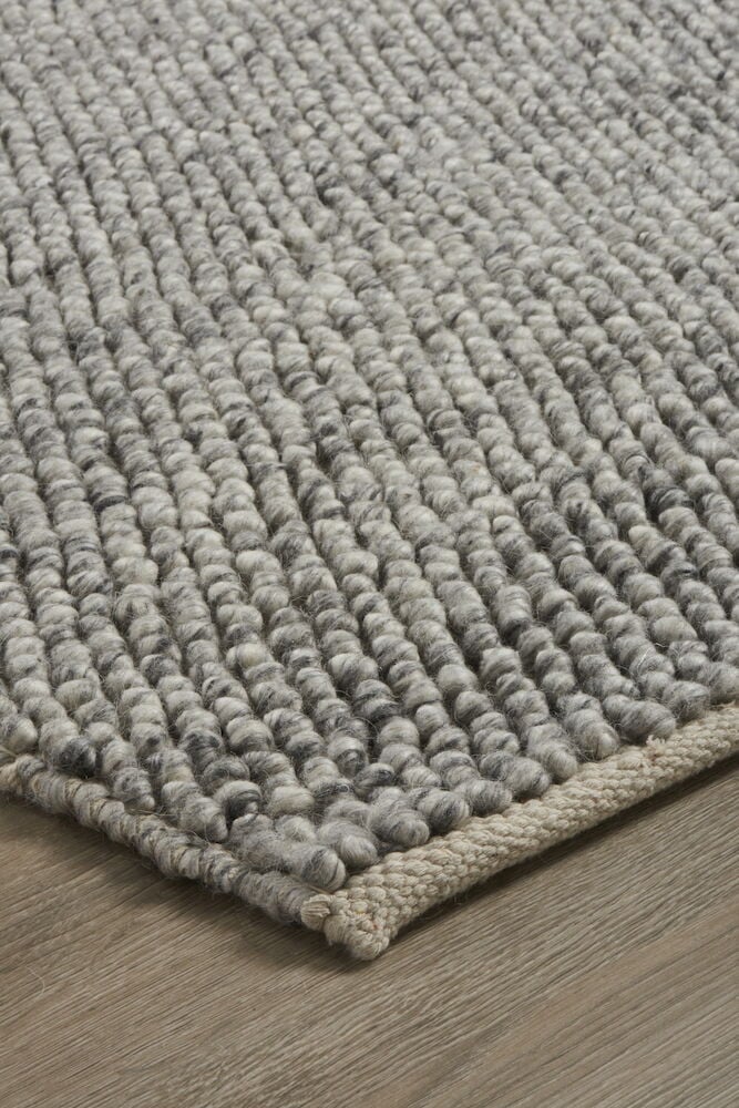 Håndvevd grå matte med små tovede ullkuler.