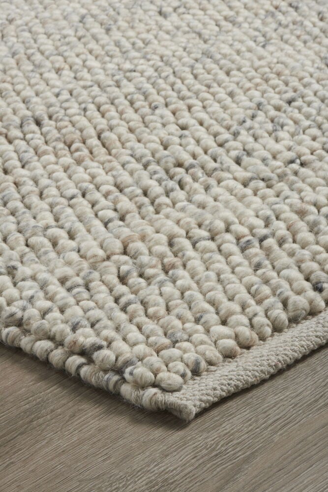 Handvävd naturfärgad ullmatta med filtbollar.