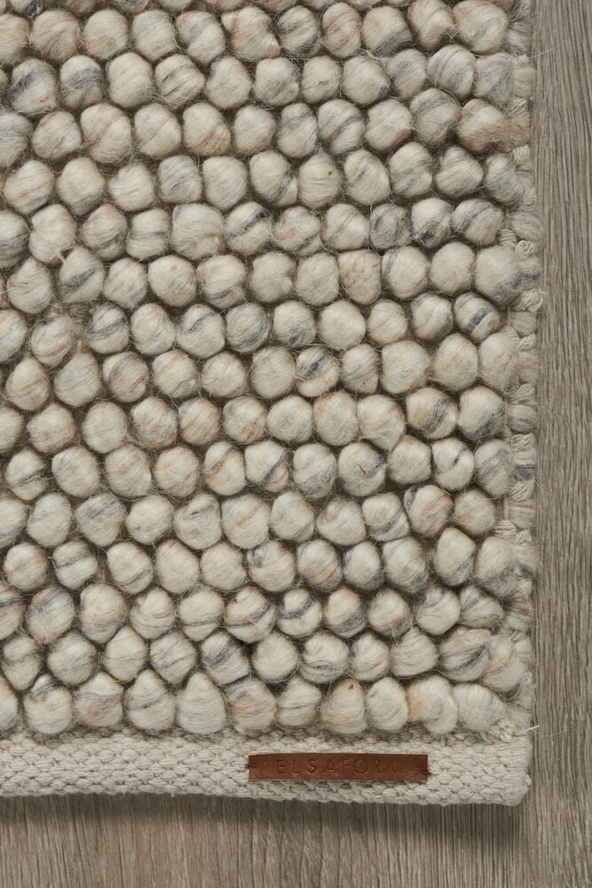 Handvävd ullmatta med tovade bollar i naturfärg.