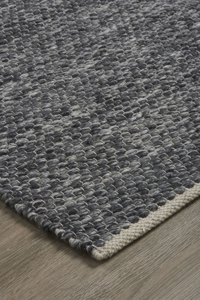 Handvävd mörkgrå matta på trägolv.