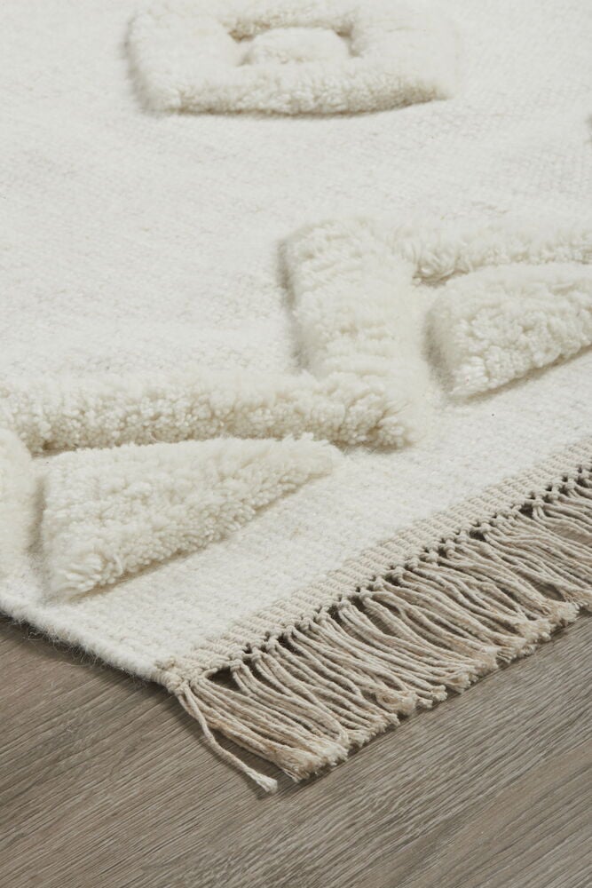 Käsin kudottu villamatto, jossa on kuvioita ja hapsuja.