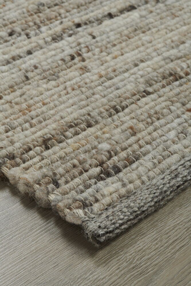 Handvävd brun matta på trägolv närbild.