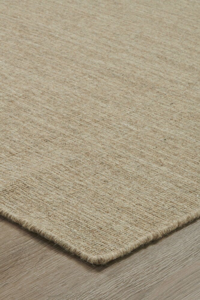 Ruskea tasokudottu matto puulattialla kulmaperspektiivissä.