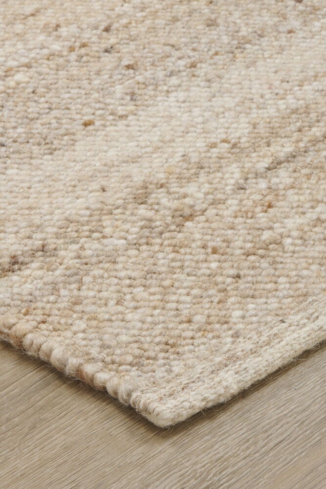 Beige käsin kudottu villamatto meleeratulla kuviolla.