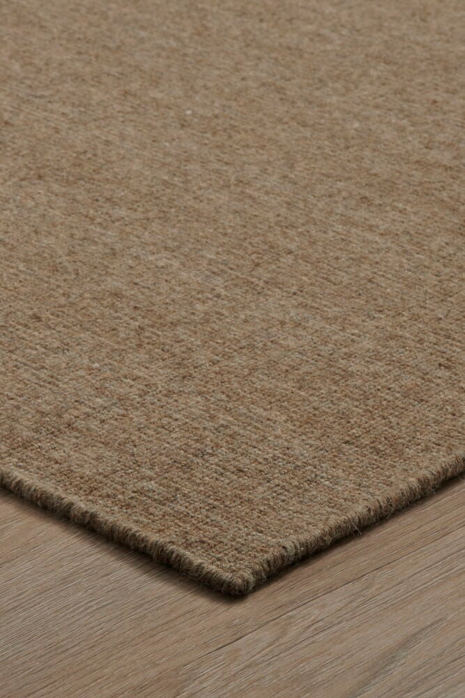 Brun handvävd dörrmatta på trägolv.