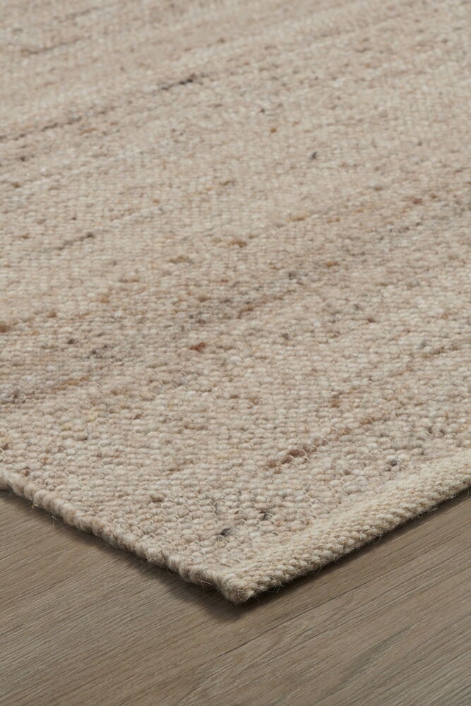 Beige handvävd ullmatta på trägolv.