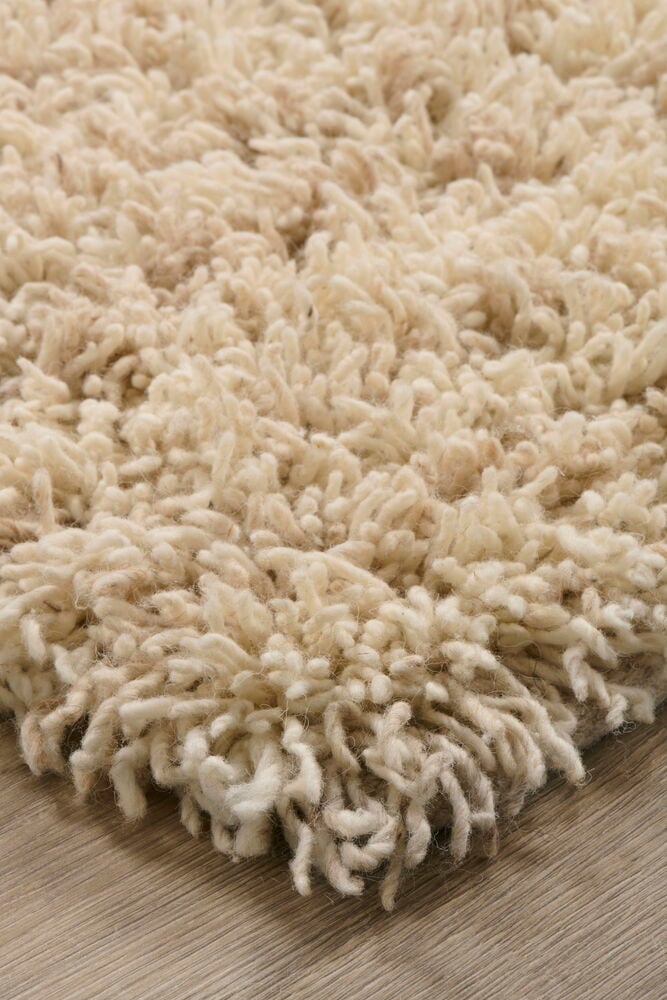 Beige långluggad matta på ljust trägolv.