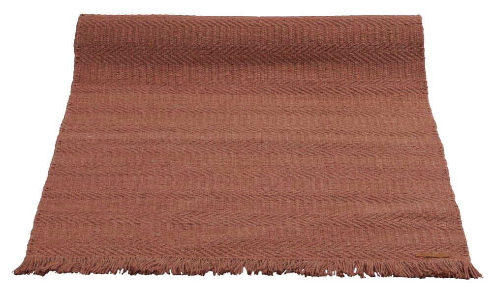 Viininpunainen matto, jossa hapsut reunoilla.