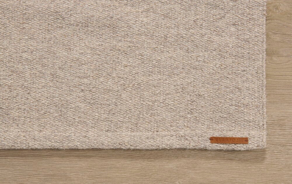 Harmaa perkaalilakana puulattialla.