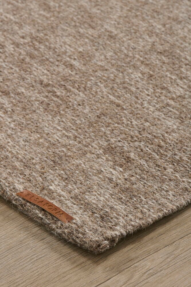 Ruskea matto, jossa on karkeaa rakennetta, puulattialla.