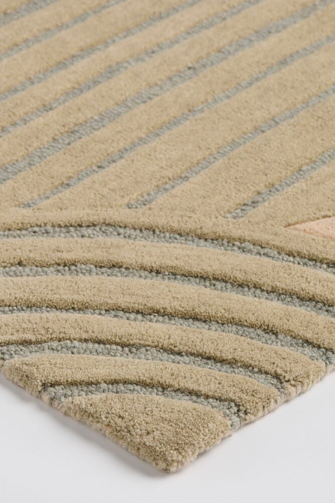 Nærbilde av et flerfarget ullteppe med teksturert geometrisk mønster i beige, grått og lyserosa.