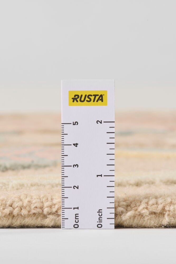 Lähikuva monivärisen villamaton sivusta mittatikun kanssa, joka esittää sen paksuutta.