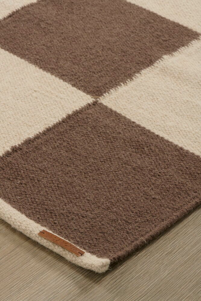 Brun Ull-matta med rutmönster i brunt och benvitt samt en liten läderetikett.