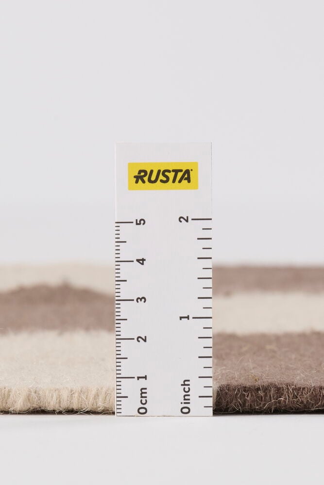 Närbild av en tvåfärgad brun och beige Brun Ull-matta, cirka 1,5 cm tjock.