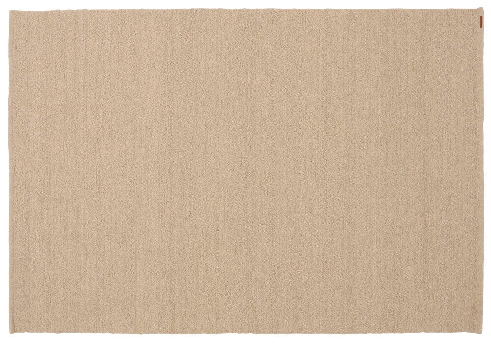 Beige suorakaiteen muotoinen matto, jossa on kuvioitu pinta ja pieni ruskea etiketti oikeassa yläkulmassa.