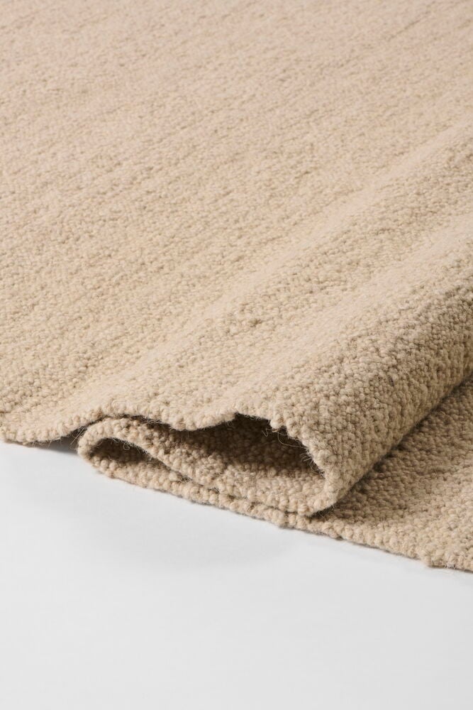 Beige Elsaform Bonnie villasekoitematto, jossa on kuvioitu pinta, osittain taitettuna.