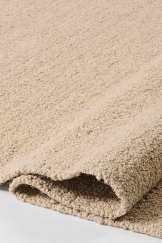 Vikt beige matta i ullblandning med synlig textur.