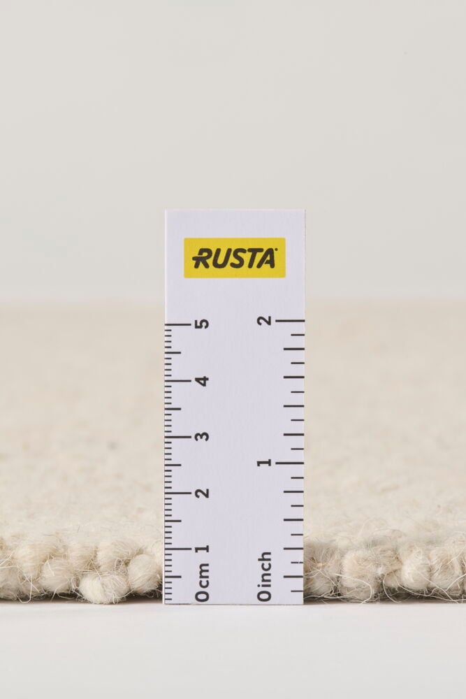 Off-white ullblandningsmatta i närbild, visar dess texturerade yta och cirka 1,5 cm lugghöjd med linjal.