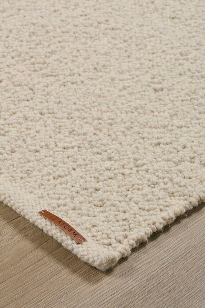 Närbild av en Off-white texturerad matta med brun varumärkesetikett på trägolv.