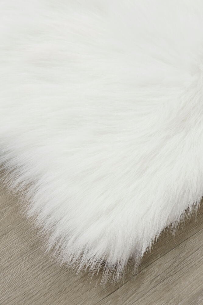 Vit konstfäll med lång lugg på trägolv.