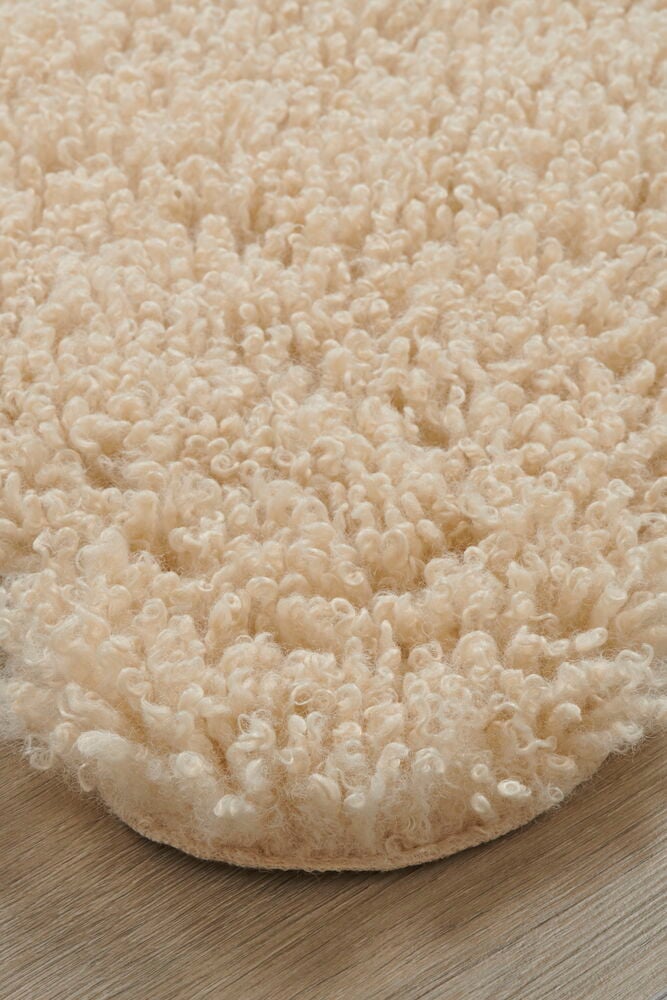 Beige konstfäll med långa lockar på golv.