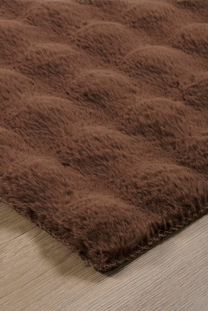 Brun konstpälsmatta Paula med texturerad yta, sydd kant på trägolv.