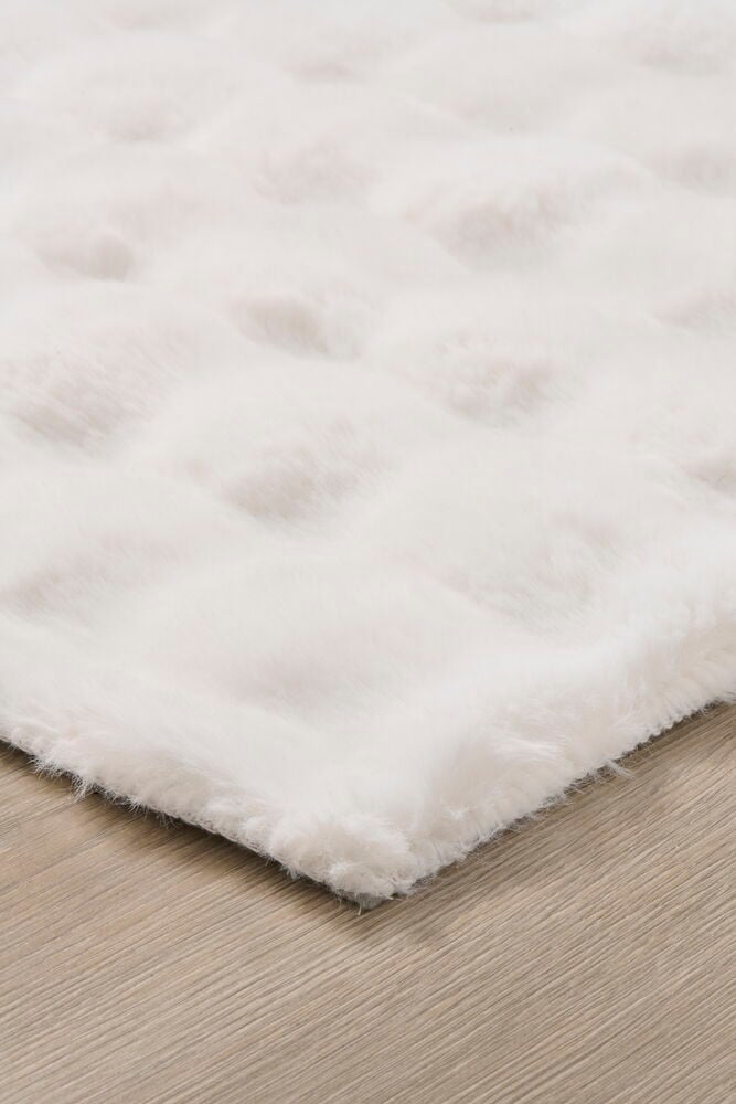 Valkoinen pörröinen matto kiiltävällä turkisrakenteella.