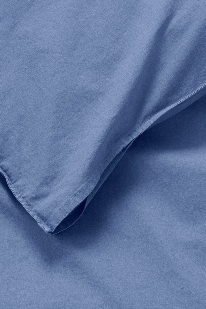 Nahaufnahme eines dusty blue Baumwoll-Bettwäsche-Sets, das gefalteten Stoff und Textur zeigt.